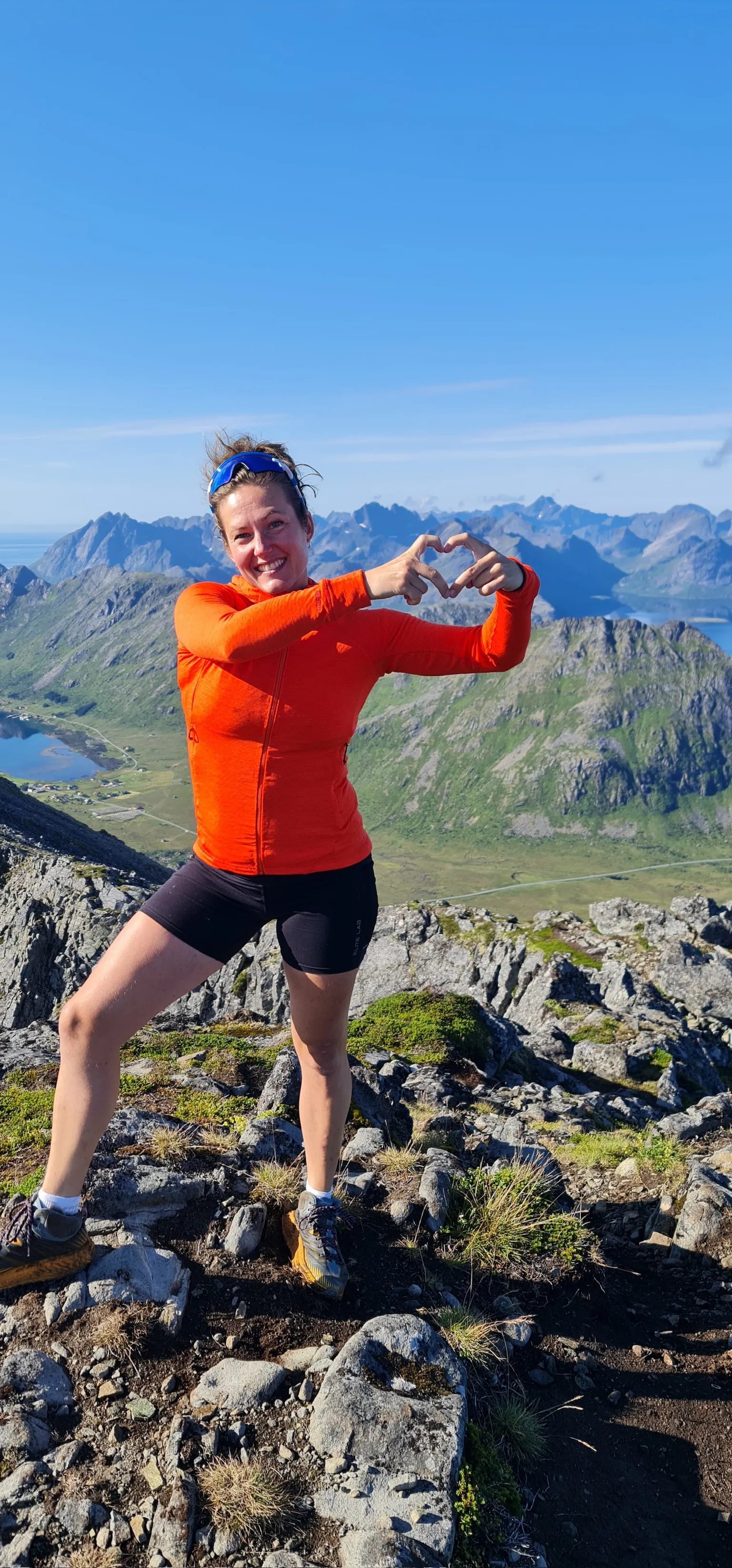Maya former et hjerte med hendene på en fjelltopp i Lofoten.